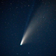 A bright yellow-white streak at center is the comet NEOWISE, against the deep blue night sky.